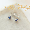 The lapis wrapped post earrings styled on linen with dried grass