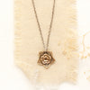 The bronze layered cactus flower necklace styled on tan linen with dried grass