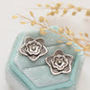 The layered cactus flower post earrings styled on a blue velvet box with dried grass