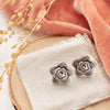 The layered cactus flower post earrings styled on wood with linen, orange velvet, and dried grass