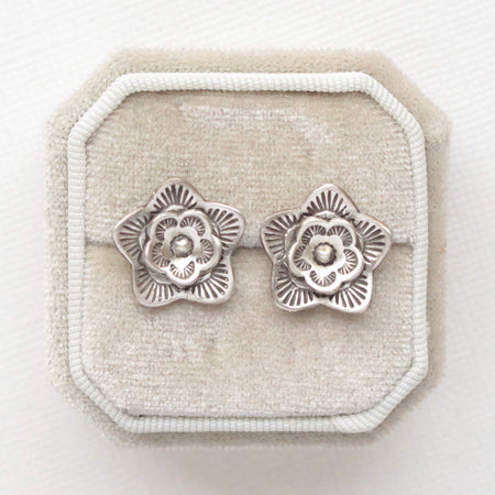 The layered cactus flower post earrings styled on a white velvet box