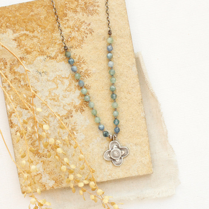 The layered talara knotted kyanite necklace styled on a tan rock with linen and dried grass