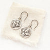 The layered wanderer coin earrings styled on tan linen
