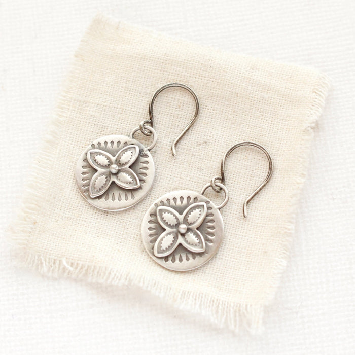 The layered wanderer coin earrings styled on tan linen