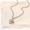The layered wanderer coin necklace styled on tan linen