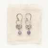 The lepidolite jolie earrings styled on tan linen