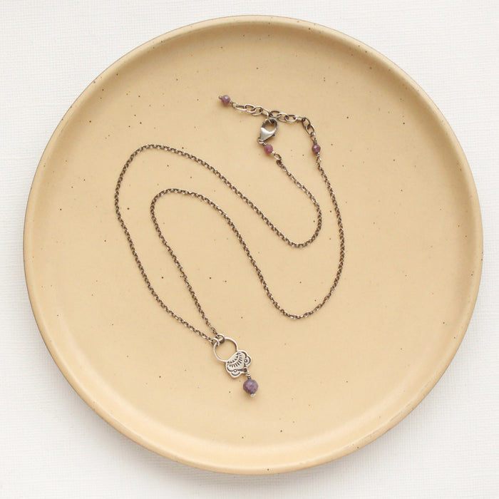 The lepidolite jolie necklace styled on a tan plate to show the adjustable lobster clasp closure