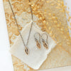 The bronze leaf earrings styled on a tan rock with the matching necklace