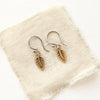 The little bronze leaf earrings styled on tan linen
