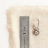 A little musana earring next to a ruler for size reference