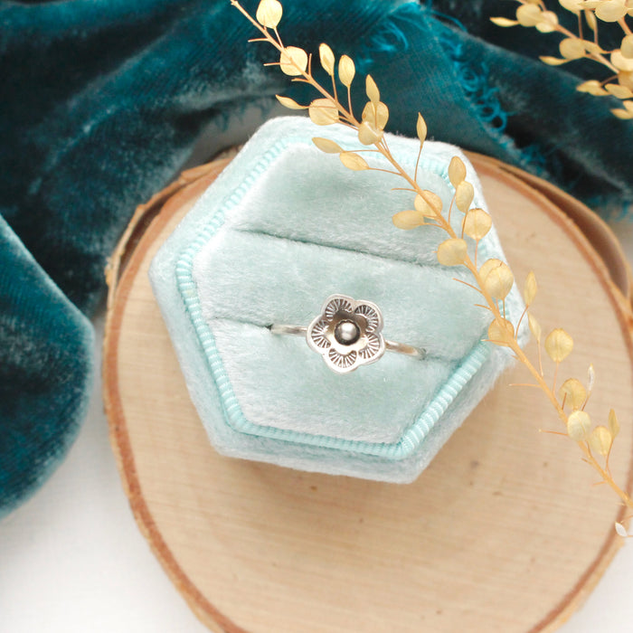 The mini cactus flower stacking ring styled in a velvet box on wood with blue velvet and dried grass