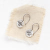 The mini soar earrings styled on tan linen