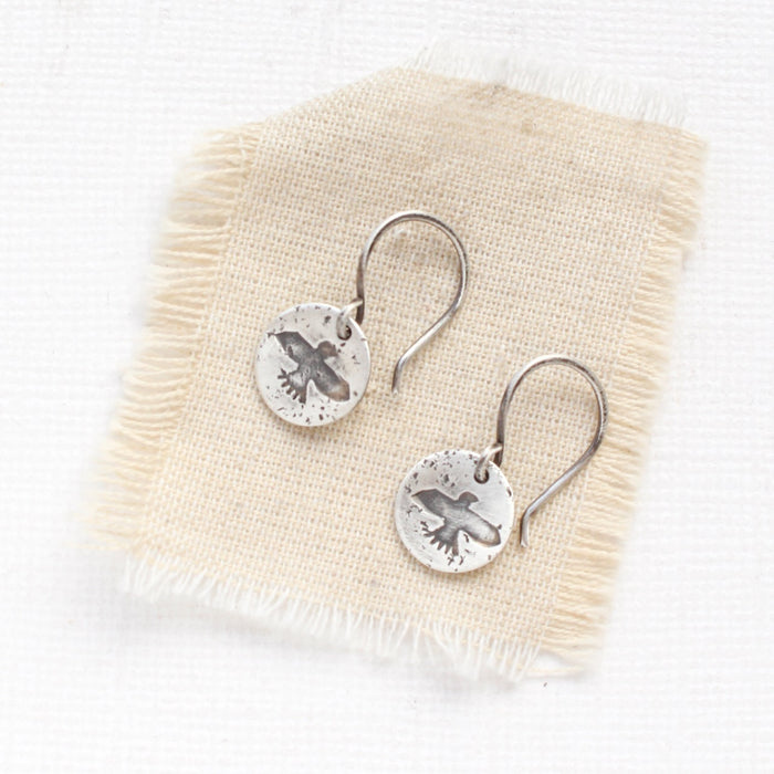 The mini soar earrings styled on tan linen