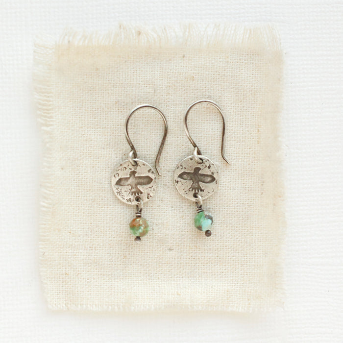 The mini soar turquoise dangle earrings styled on tan linen