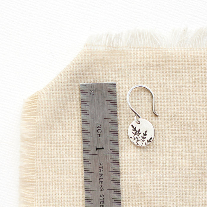 A mini sprout earring next to a ruler for size reference