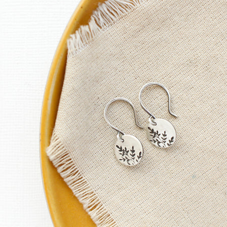 The mini sprout earrings styled on a yellow plate with tan linen