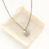 The mini sprout pearl charm necklace styled on tan linen
