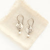 The mini sprout pearl dangle earrings styled on tan linen
