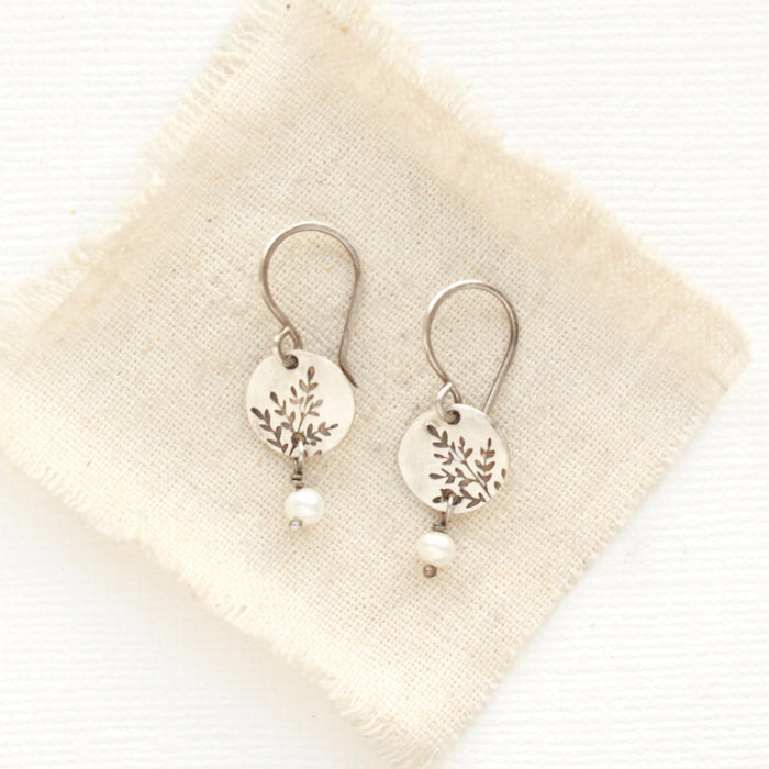 The mini sprout pearl dangle earrings styled on tan linen