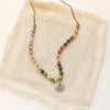 The mini sprout rainbow tourmaline necklace styled on tan linen