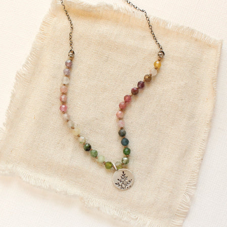 The mini sprout rainbow tourmaline necklace styled on tan linen