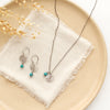 The mini sprout turquoise necklace styled on a tan plate with the matching earrings