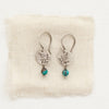 The mini sprout turquoise dangle earrings styled on tan linen