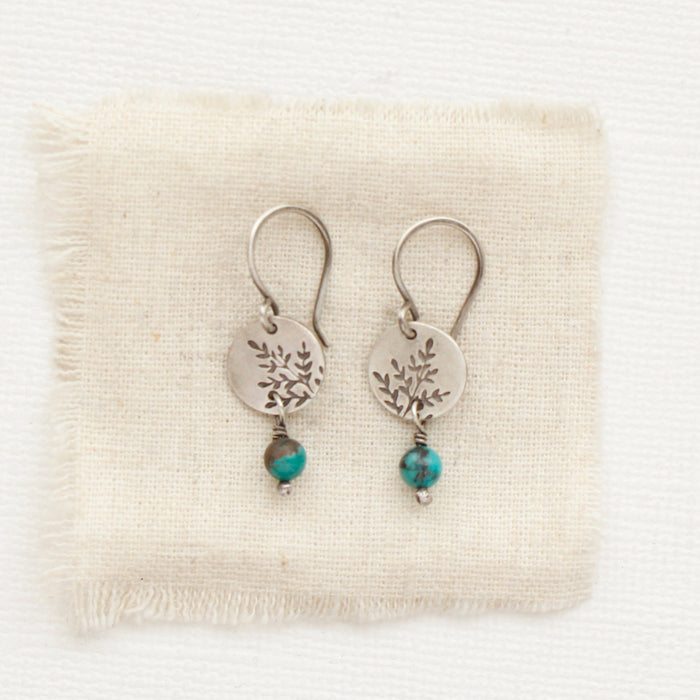 The mini sprout turquoise dangle earrings styled on tan linen
