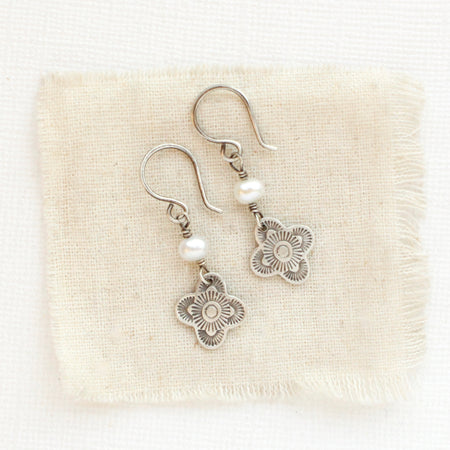 The mini talara pearl earrings styled on tan linen