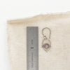 A mini talara shield earring next to a ruler for size reference