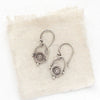 The mini talara shield earrings styled on tan linen