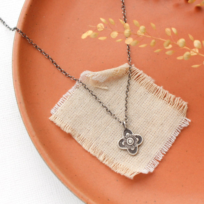 The mini talara necklace styled on an orange plate with linen and dried grass