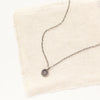 The mini talara sun necklace styled on tan linen