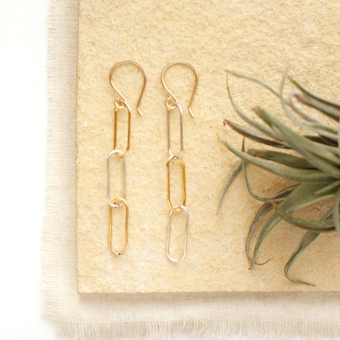 The mixed metal paperclip earrings styled on a tan rock with linen and an air plant