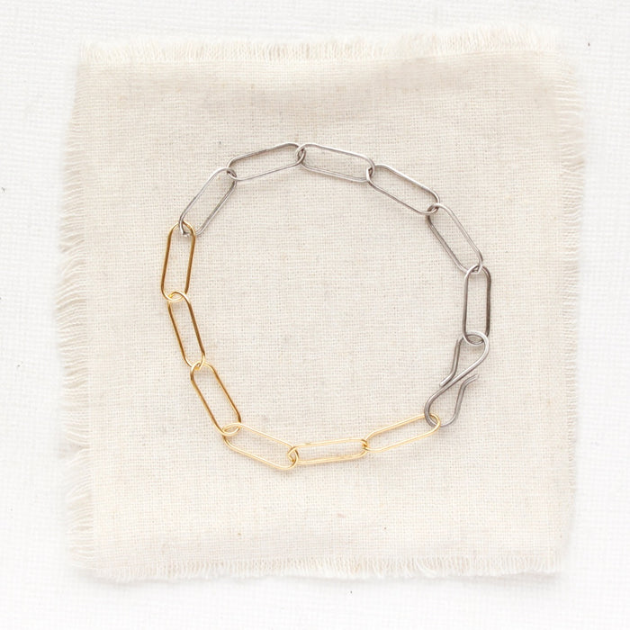 The mixed metal paperclip bracelet styled on tan linen