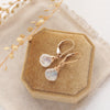 The moonstone drop earrings styled on a yellow velvet box with linen and dried grass