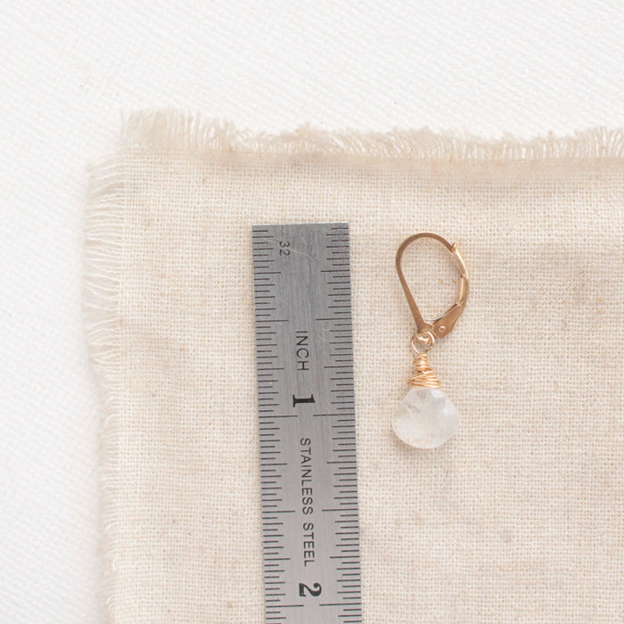 A moonstone drop earring next to a ruler for size reference