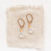 The moonstone drop earrings styled on tan linen