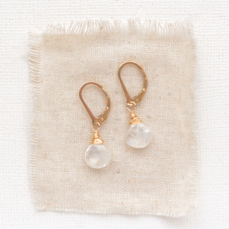 The moonstone drop earrings styled on tan linen