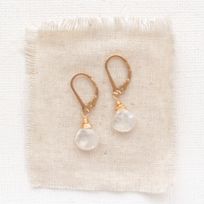 The moonstone drop earrings styled on tan linen