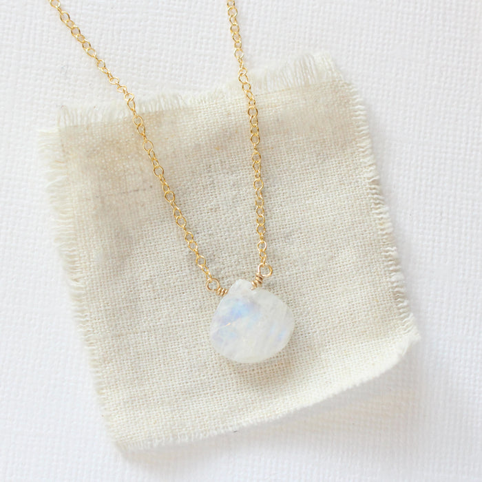 The gold moonstone drop necklace styled on tan linen