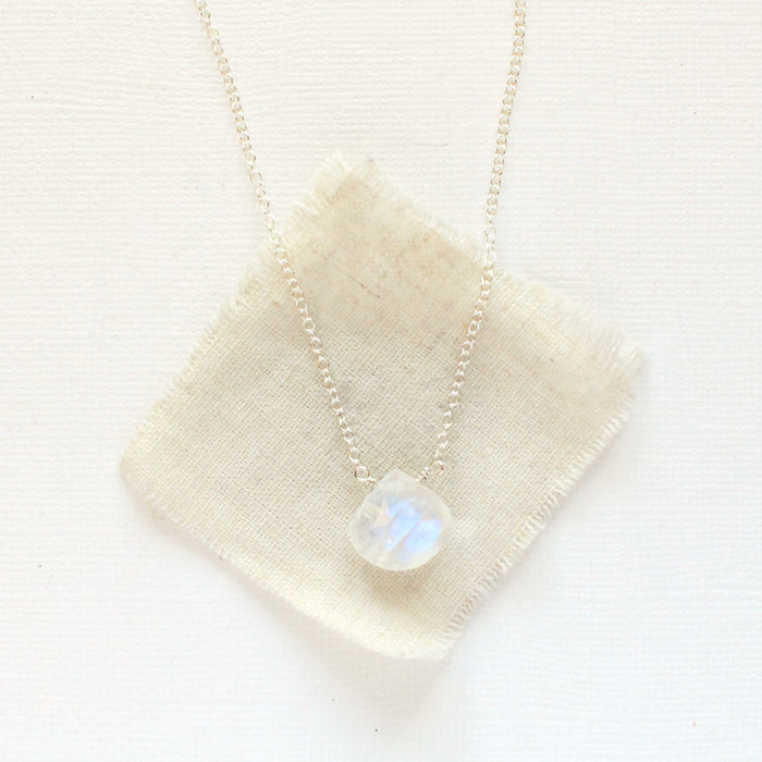 The silver moonstone drop necklace styled on tan linen