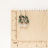 The moonstone and emerald fringe earrings on a wooden ruler for size reference