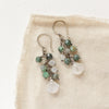 The moonstone and emerald fringe earrings styled on tan linen