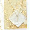 The moonstone gold lariat necklace styled on a tan rock with linen and dried grass