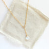The moonstone gold lariat necklace styled on tan linen