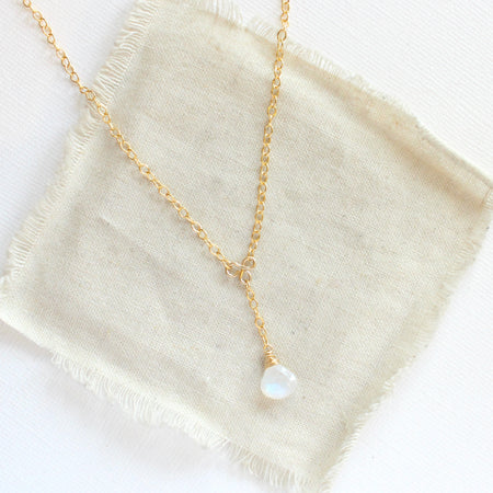 The moonstone gold lariat necklace styled on tan linen