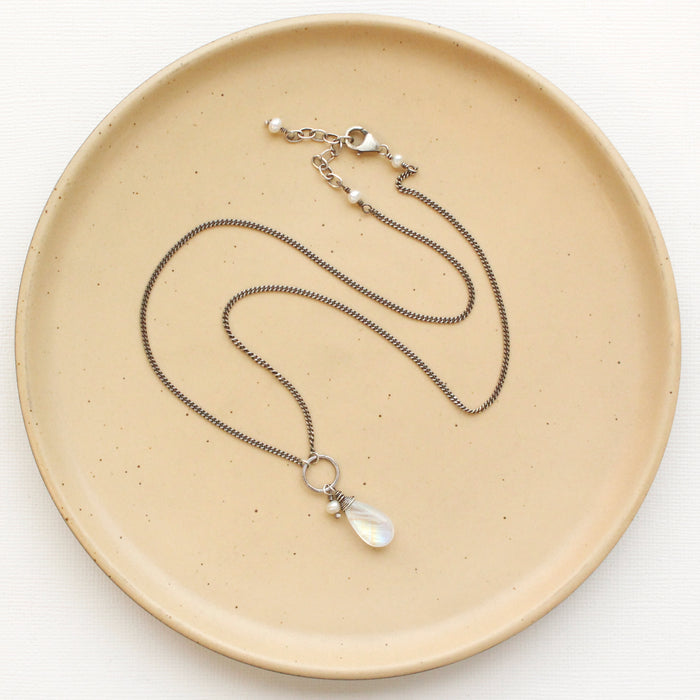 The moonstone and pearl necklace styled on a tan plate to show the adjustable lobster clasp closure