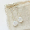 The moonstone swing earrings styled on tan linen
