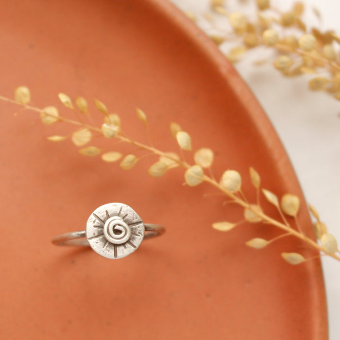 The musana ring styled on an orange plate with dried grass